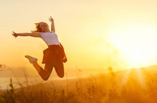 Happy woman   jump,  rejoices, laughs  on sunset in nature